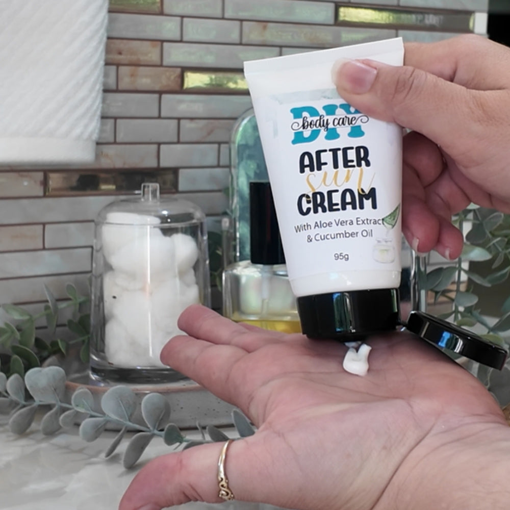 A hand holds a white tube with open black flip-top cap over the palm of another hand while squeezing some white cream out. The tube is labeled as After Sun Cream.