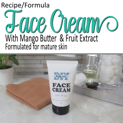 A product cover photo with the text FACE CREAM in teal cursive writing in the top half of the image against a white background. Further text indicates this is made with Mango Butter and Fruit extract.  The bottom half has a image of a  a white tube with black lid standing on a bathroom counter top surrounded by accessories like face cloth, rings and bottle or perfume.  The tube is labeled as Face Cream