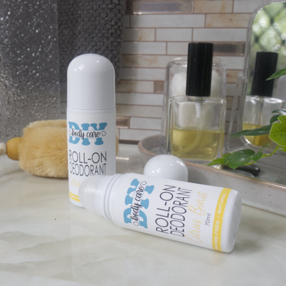 Rwo bottles of Roll-on deodorant displayed on a bathroom counter.  One bottle stands upright with a domed lid while another lays flat on the bench with the lid removed showing the rolling mechanism. 