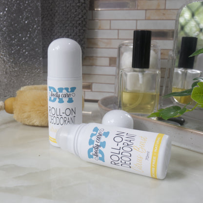 Rwo bottles of Roll-on deodorant displayed on a bathroom counter.  One bottle stands upright with a domed lid while another lays flat on the bench with the lid removed showing the rolling mechanism. 