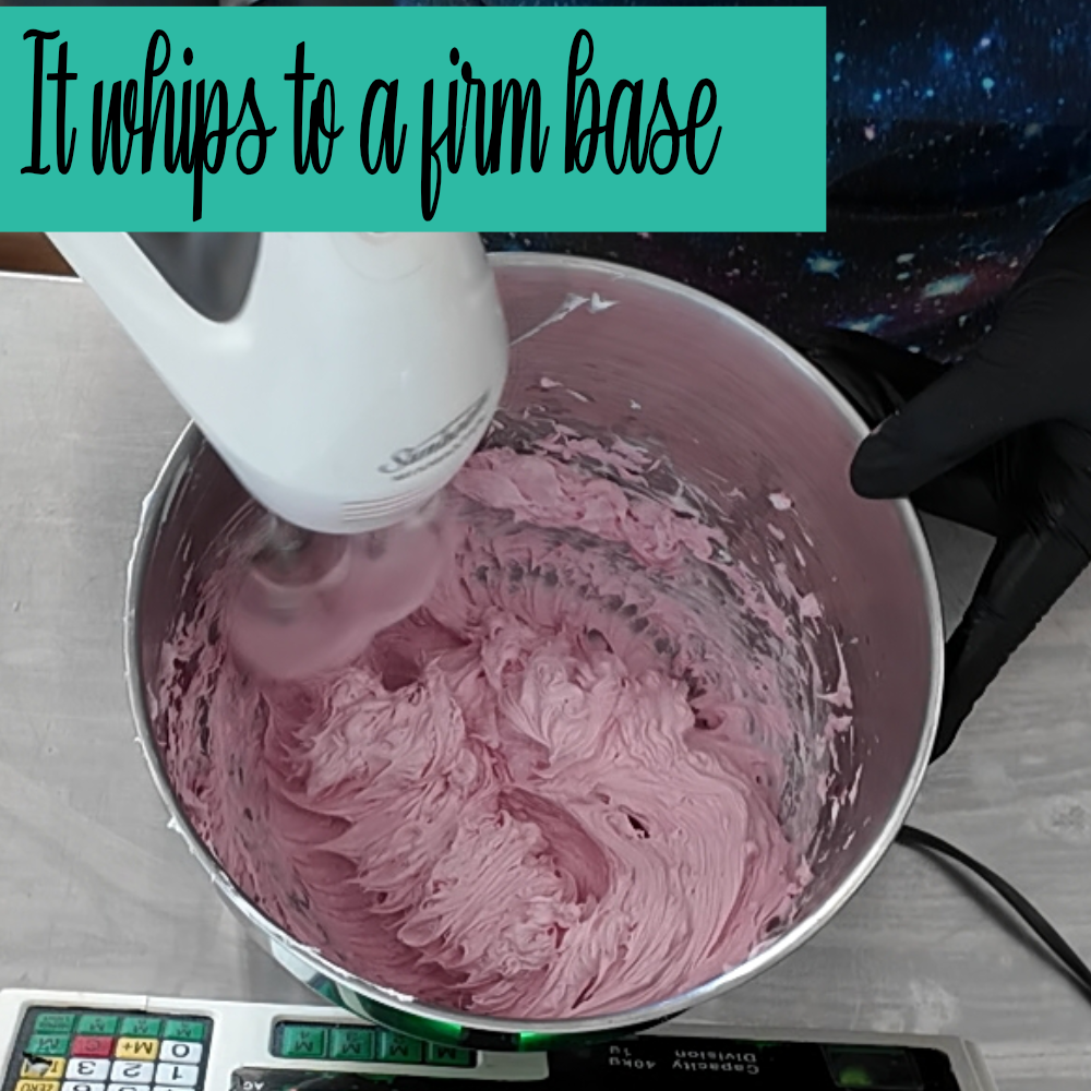 A person is using an eletric hand mixer to whip a bowl of pink soap.   The text reads IT WHIPS TO A FIRM BASE